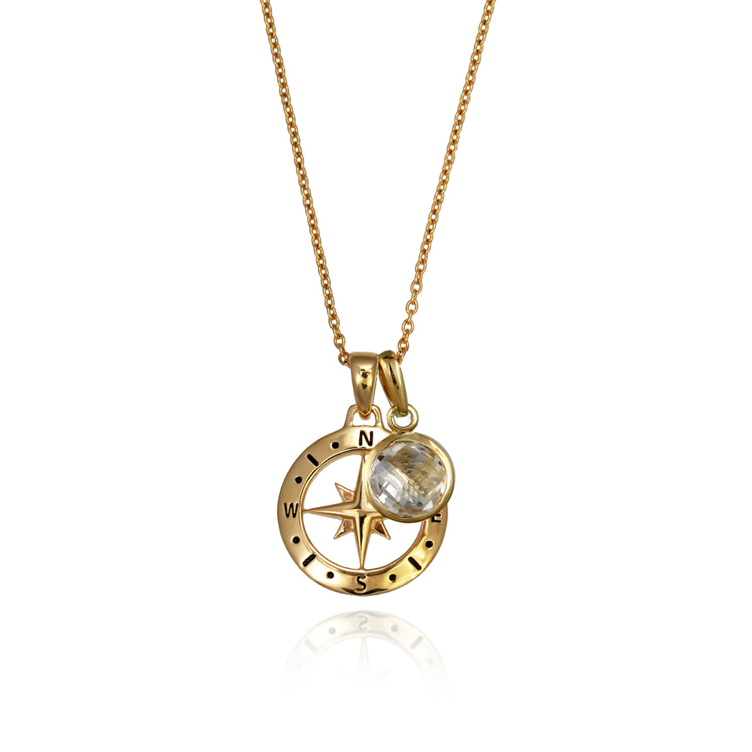 A gold versible compass necklace with a white topaz april birthstone charm and chain against a white background