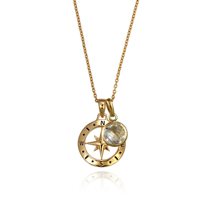 A gold versible compass necklace with a white topaz april birthstone charm and chain against a white background