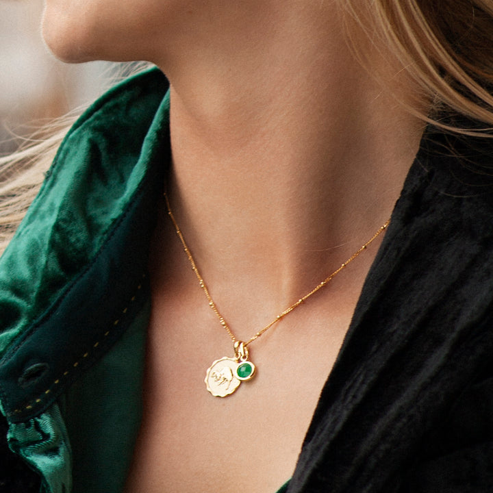 Model wearing a gold zodiac and green quartz birthstone necklace