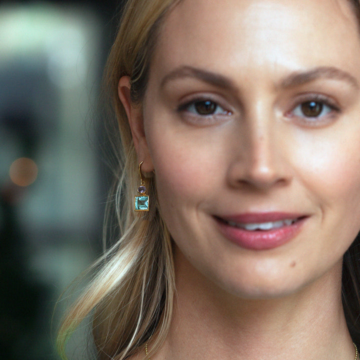 Model wearing 18ct gold vermeil blue topaz and amethyst square drop earrings