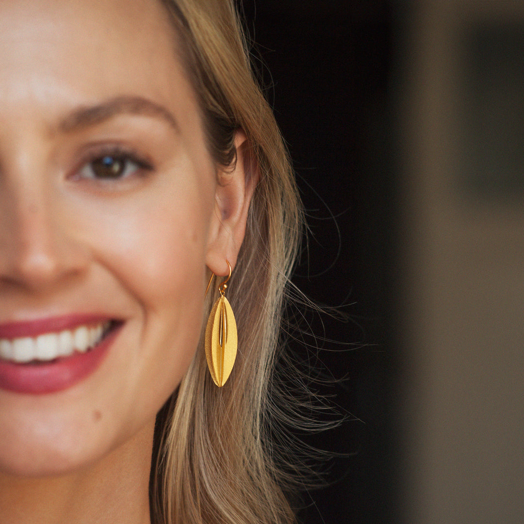 Model wearing contemporary gold drop earrings