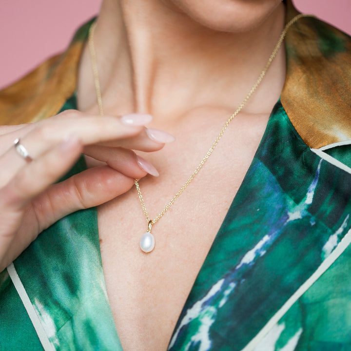Pearl necklace in gold worn with a green shirt