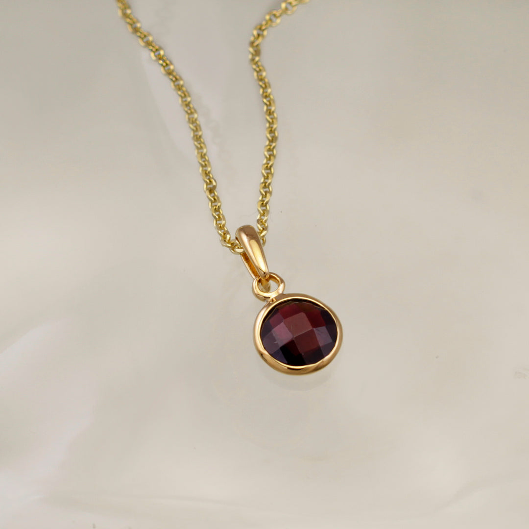 Garnet pendant set in gold vermeil with chain on gray background