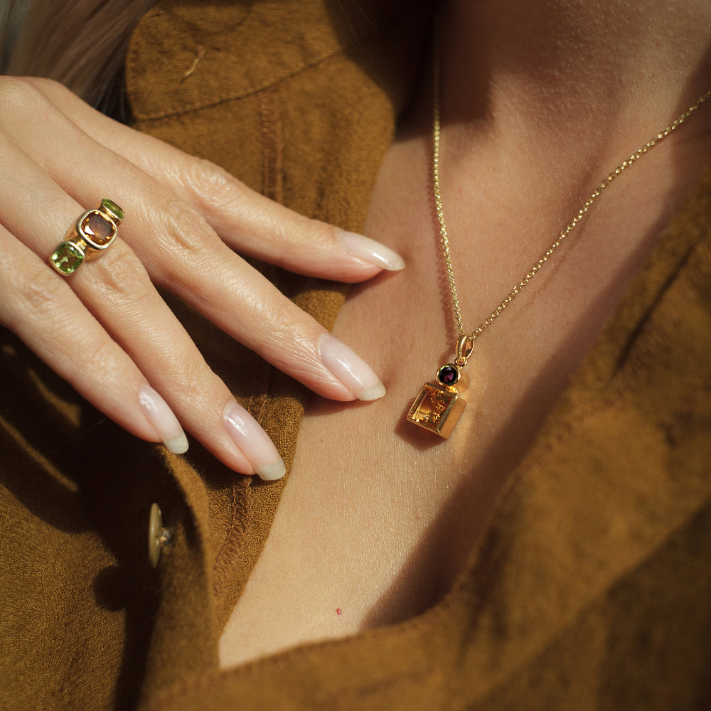Close-up of model wearing a gold vermeil citrine and garnet pendant necklace and ring