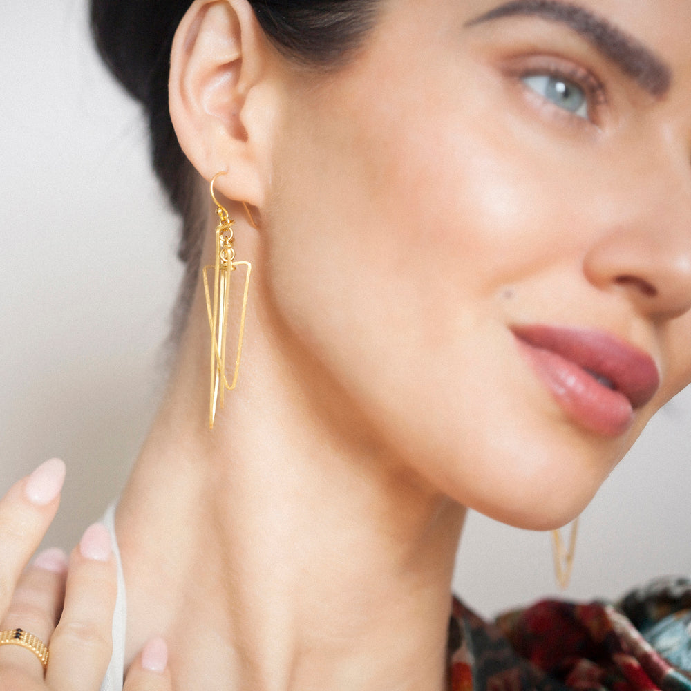 Close-up of model wearing 18ct gold vermeil geometric long drop earrings
