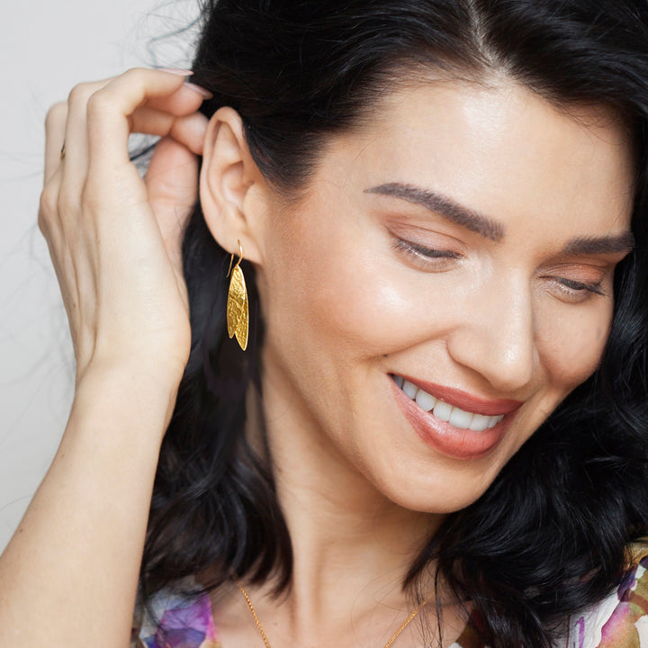 Woman wearing gold earrings with a neutral background