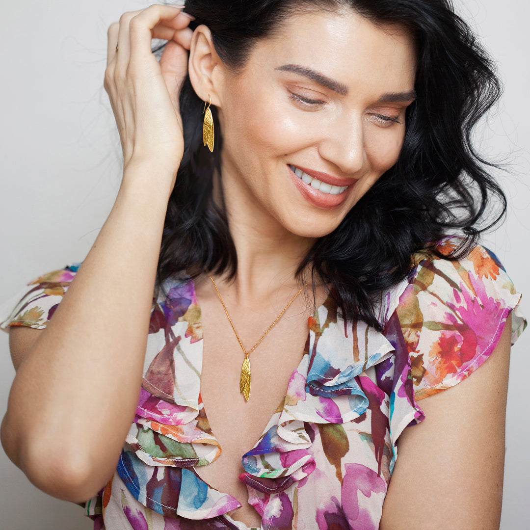 Woman wearing gold earrings and matching necklace with floral blouse