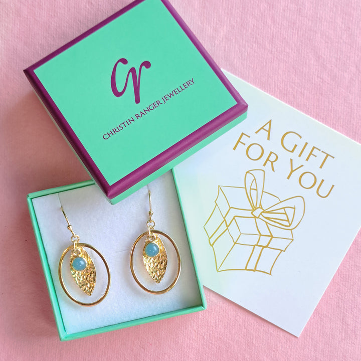 A pair of shiny gold  and blue chalcedony earrings in Christin Ranger Jewellery branded gift box and card.