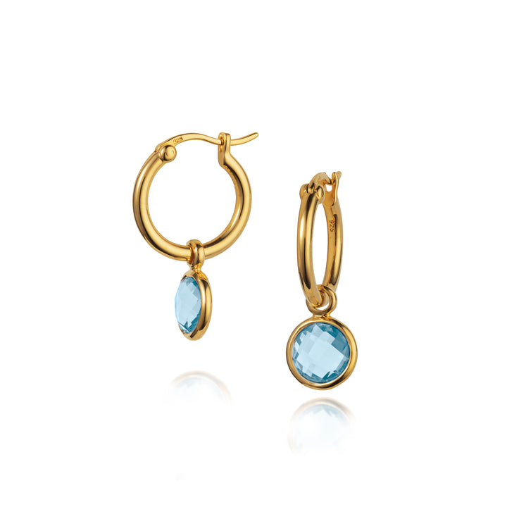 Gold hoop earrings with blue gemstones on a white background
