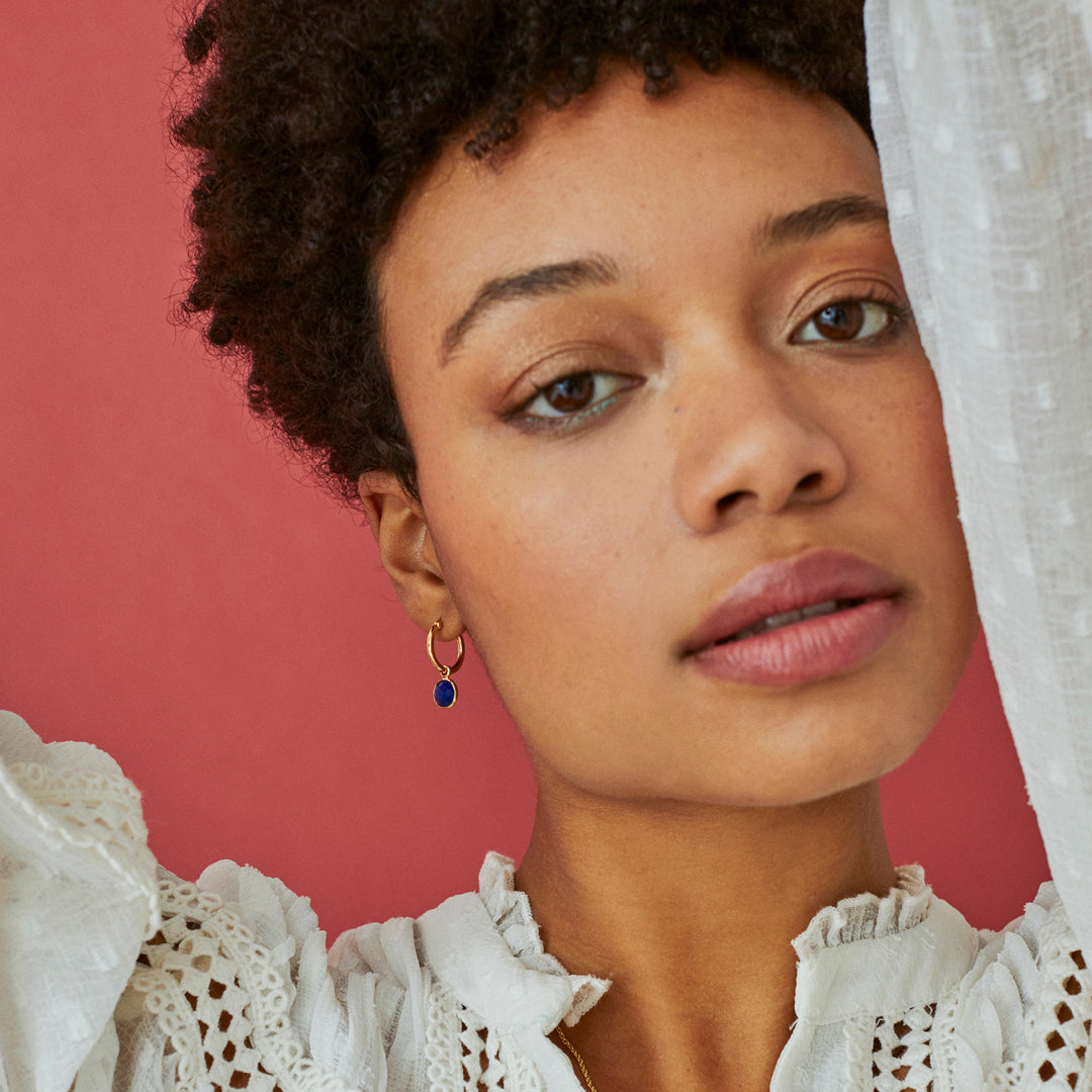 Model wearing gold hoop earrings with lapis lazuli earrings