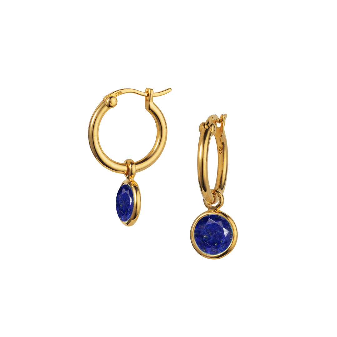 Gold huggie hoop earrings with deep blue gemstones on a white background