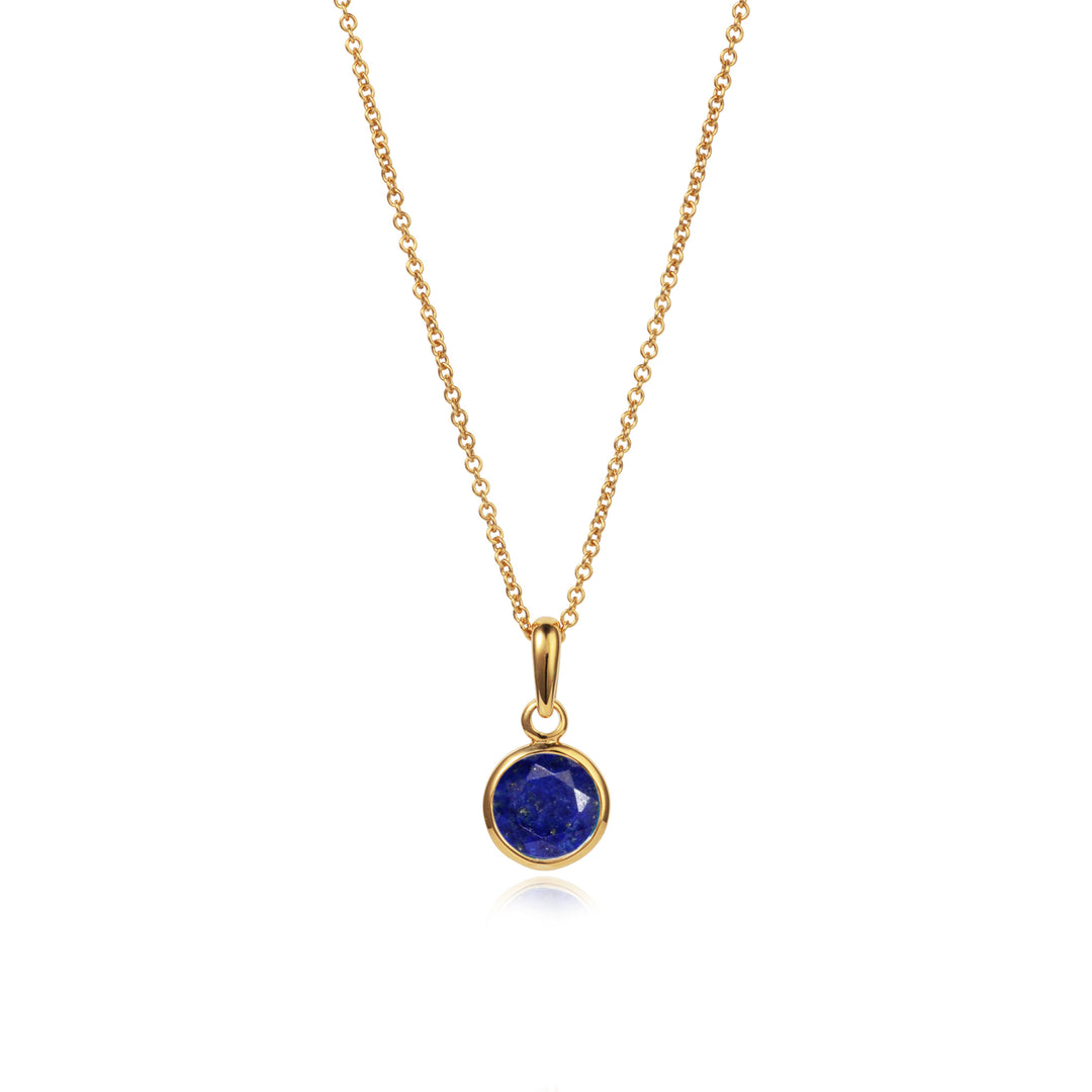 Dainty gold necklace with a round blue lapis lazuli stone and chain on white background