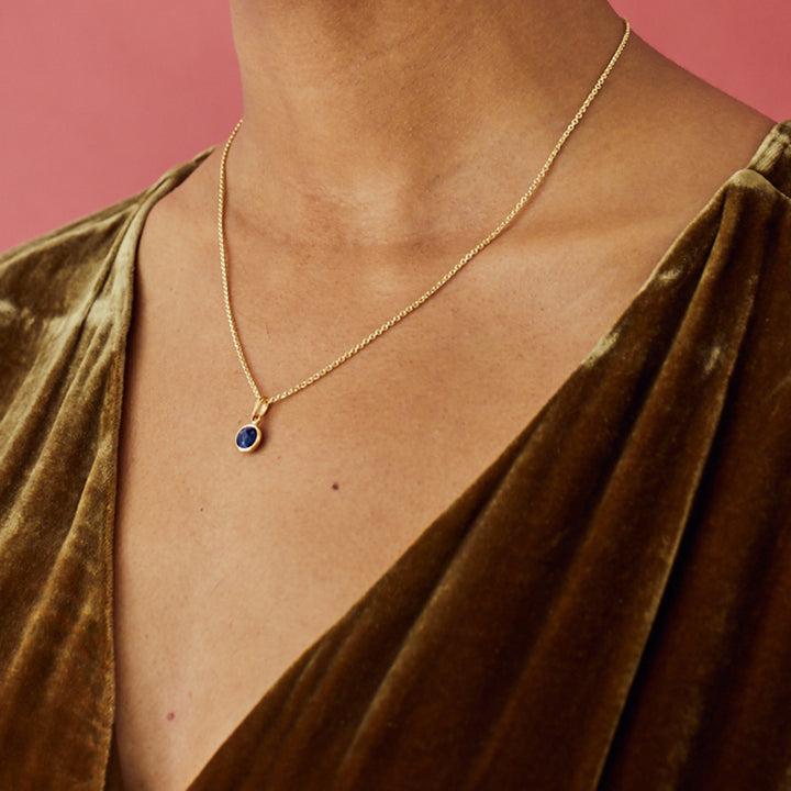 Close-up of model wearing a pretty gold lapis lazuli gemstone necklace with a velvet dress.