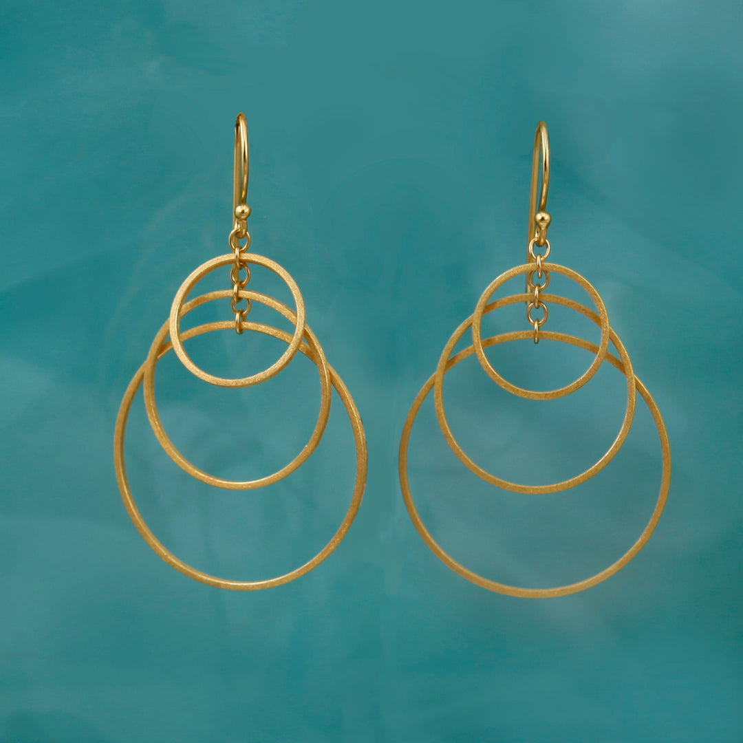 Gold three hoop earrings on a teal background
