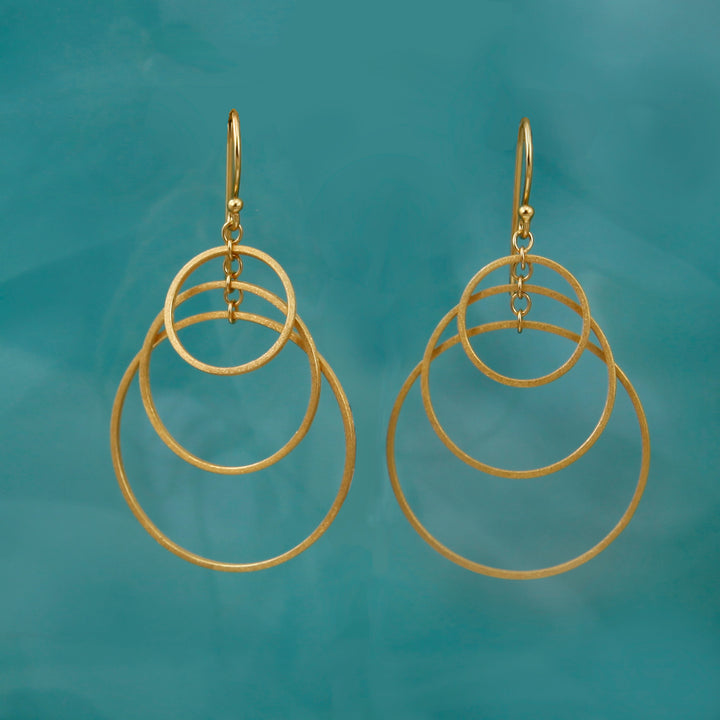 Gold three hoop earrings on a teal background