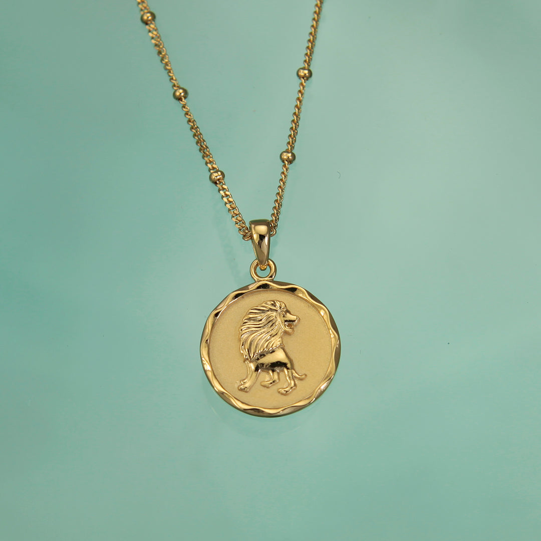 Gold Leo zodiac star sign necklace pendant on a teal background