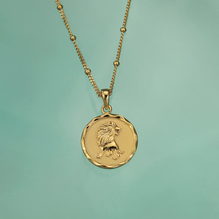 Gold Leo zodiac star sign necklace pendant on a teal background