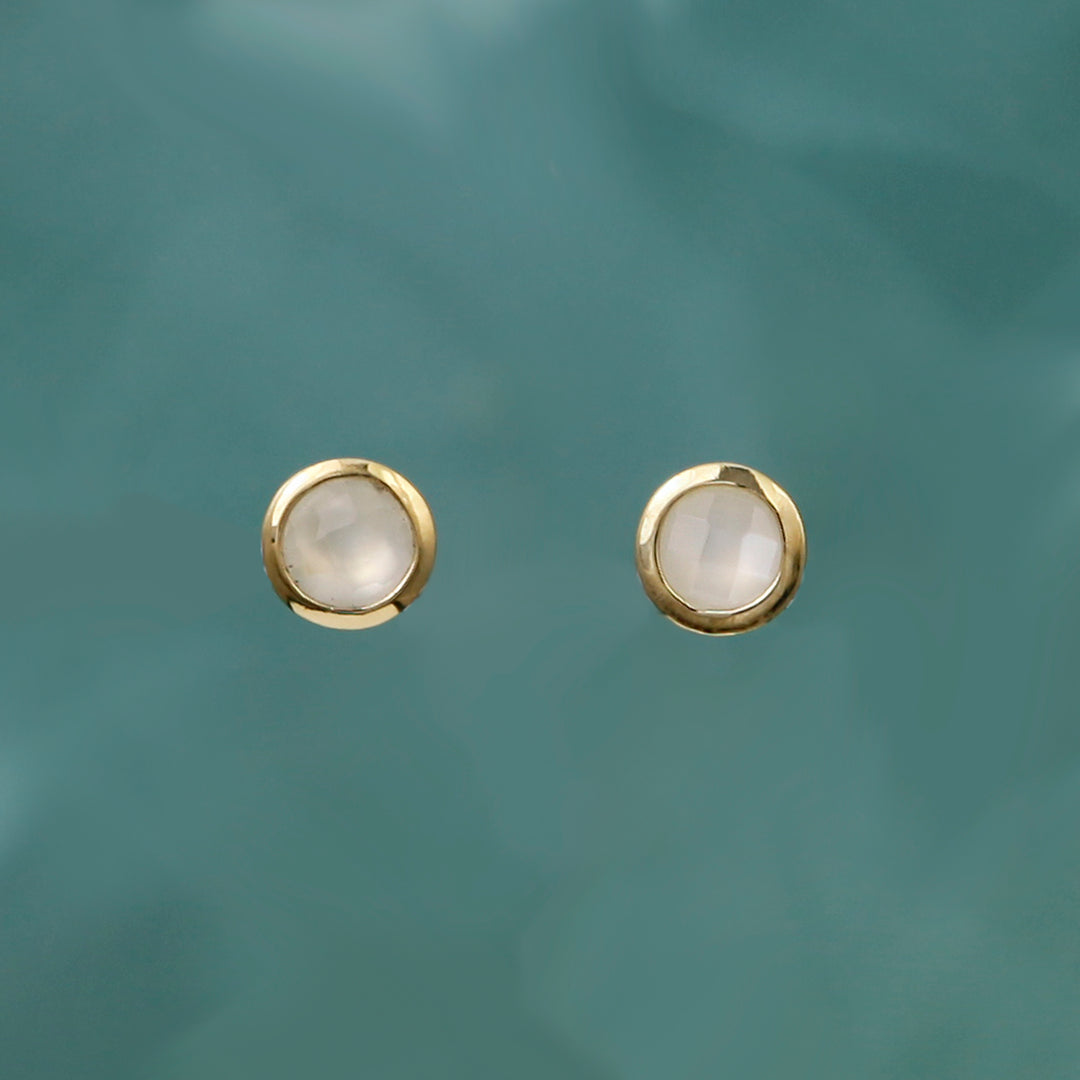 Gold moonstone post earrings on aqua background.
