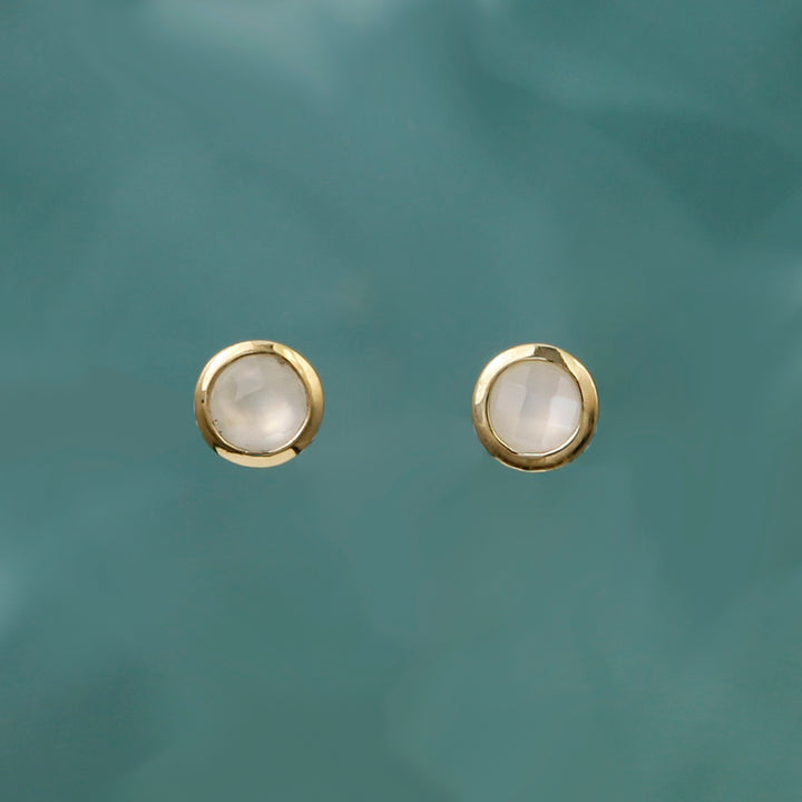 Gold moonstone post earrings on aqua background.