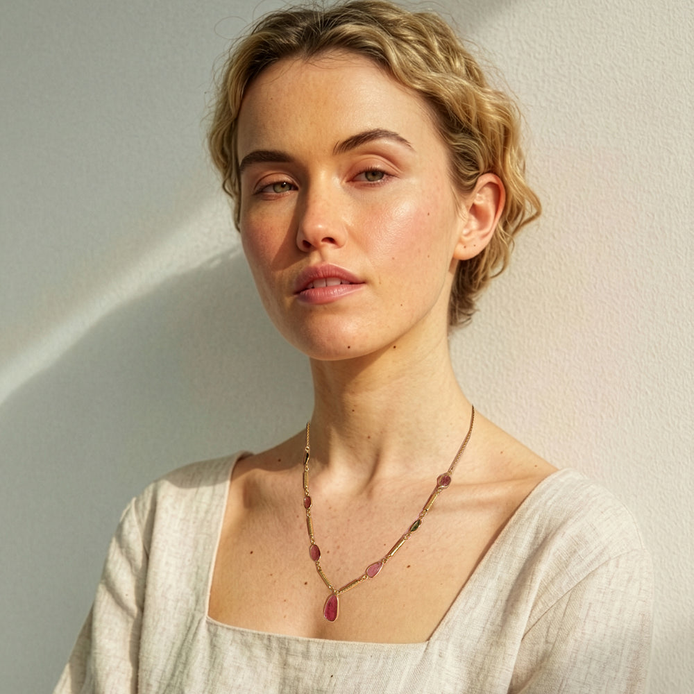 Woman wearing a gold pendant necklace with multi-colour tourmaline gemstones.