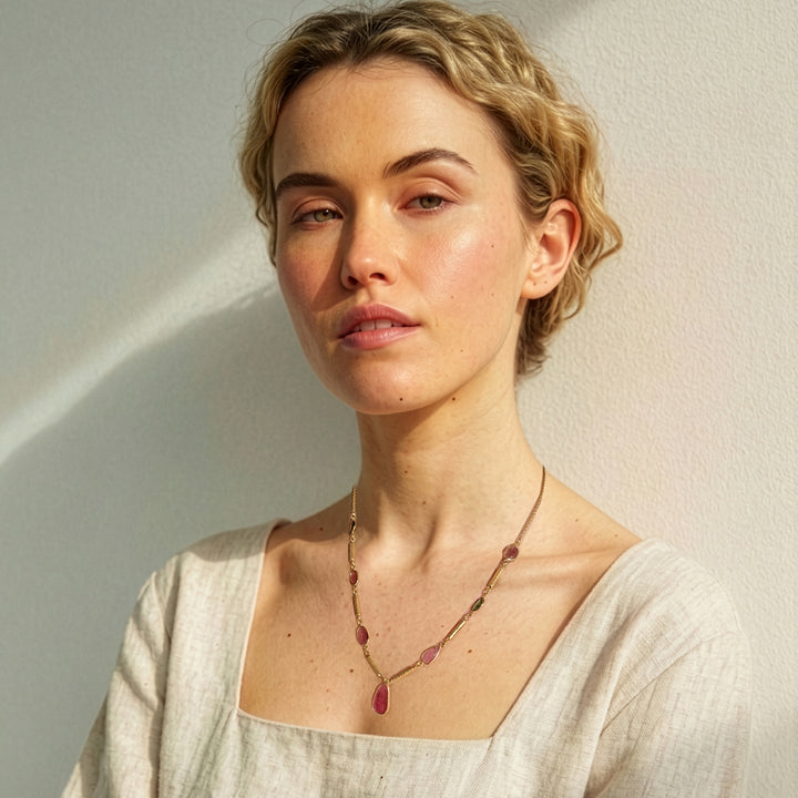 Woman wearing a gold pendant necklace with multi-colour tourmaline gemstones.