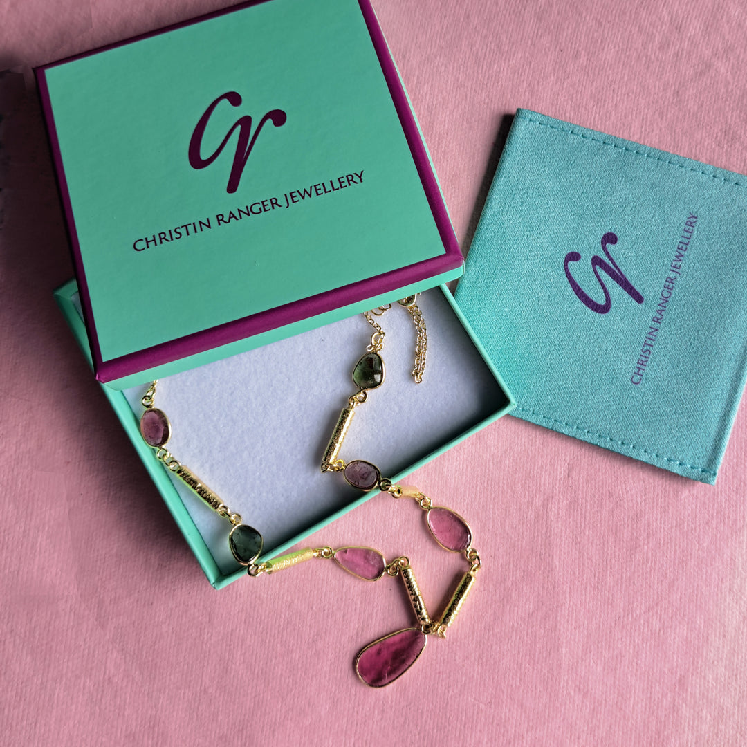 Gold tourmaline necklace in Christin Ranger Jewellery gift packaging on a pink background.