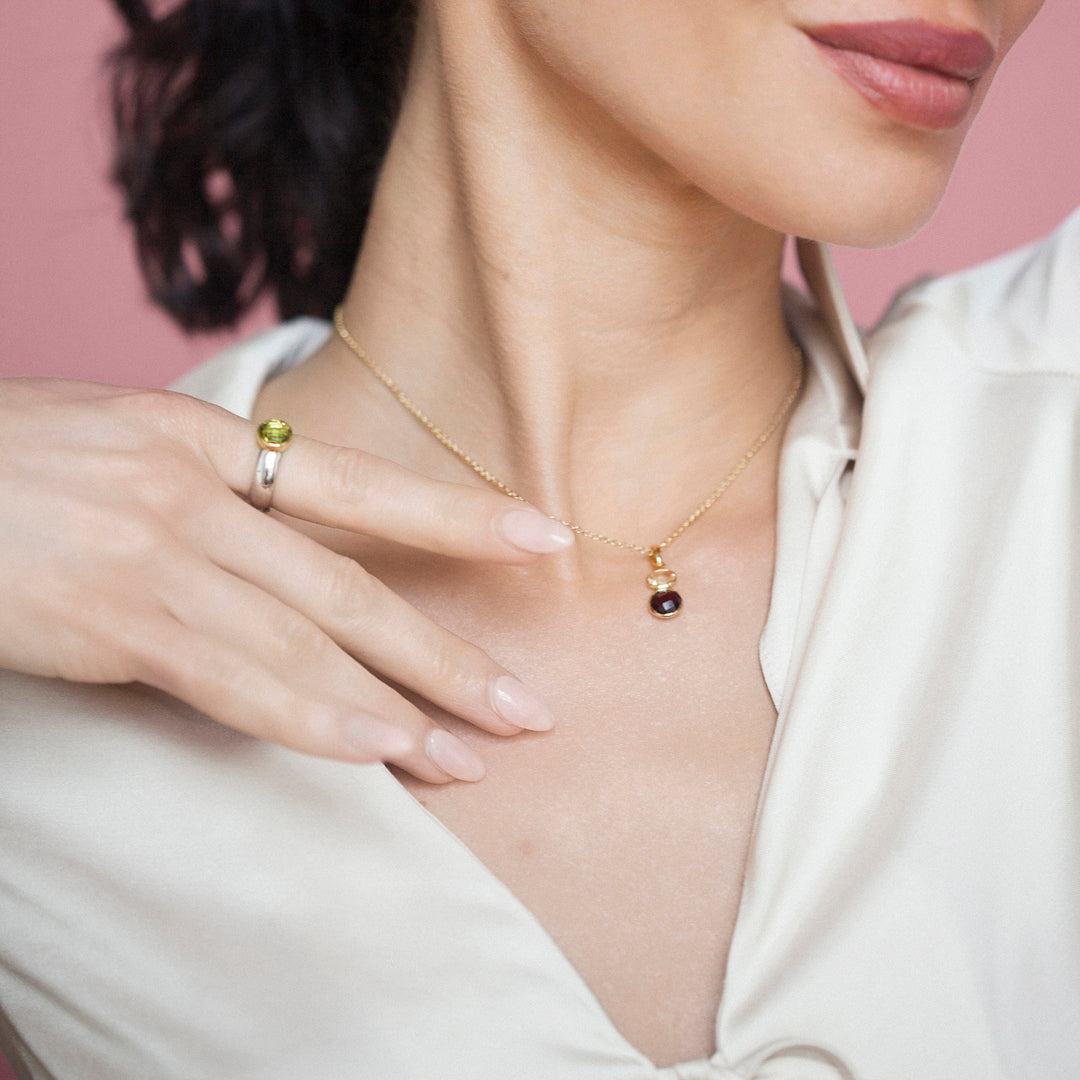 Woman wearing a gold necklace with a garnet and citrine pendant