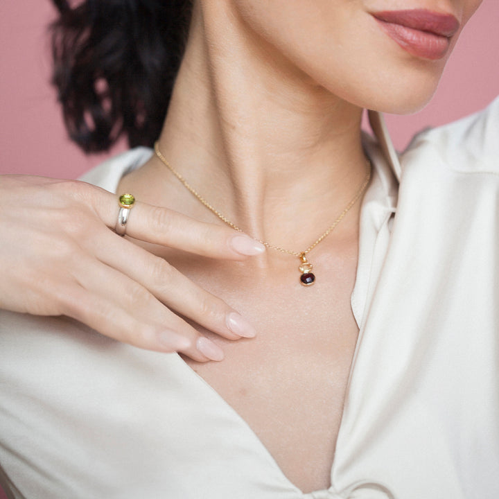 Woman wearing a gold necklace with a garnet and citrine pendant