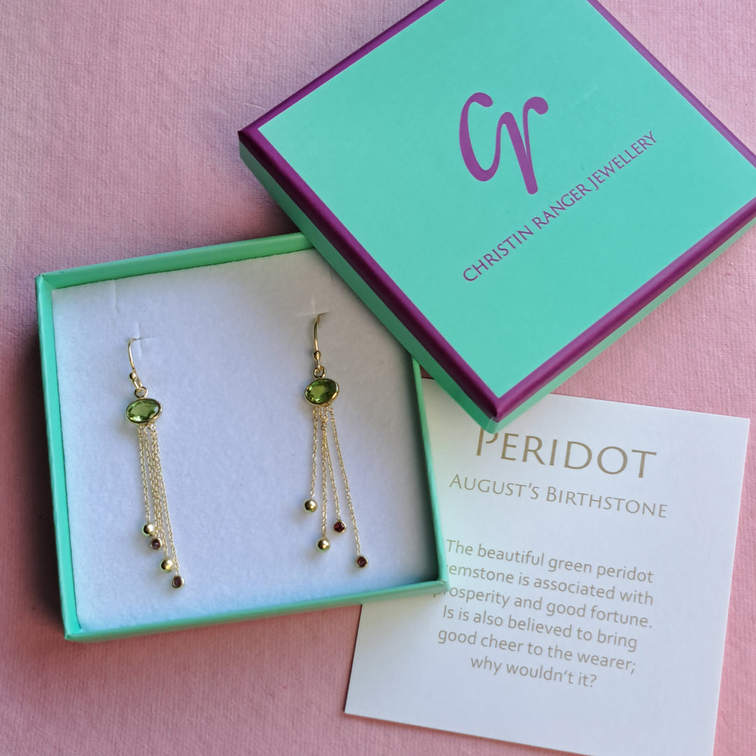 Gold peridot gemstone earrings with chain drops ending in garnets and gold balls packaged in Christin Ranger Jewellery gift box.