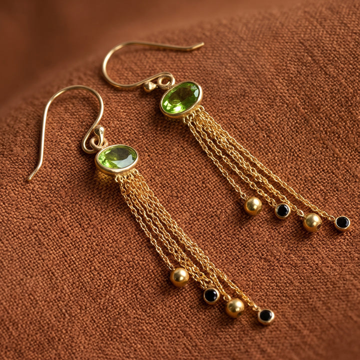 18ct gold vermeil peridot chandelier drop earrings with garnets on a sienna coloured linen background