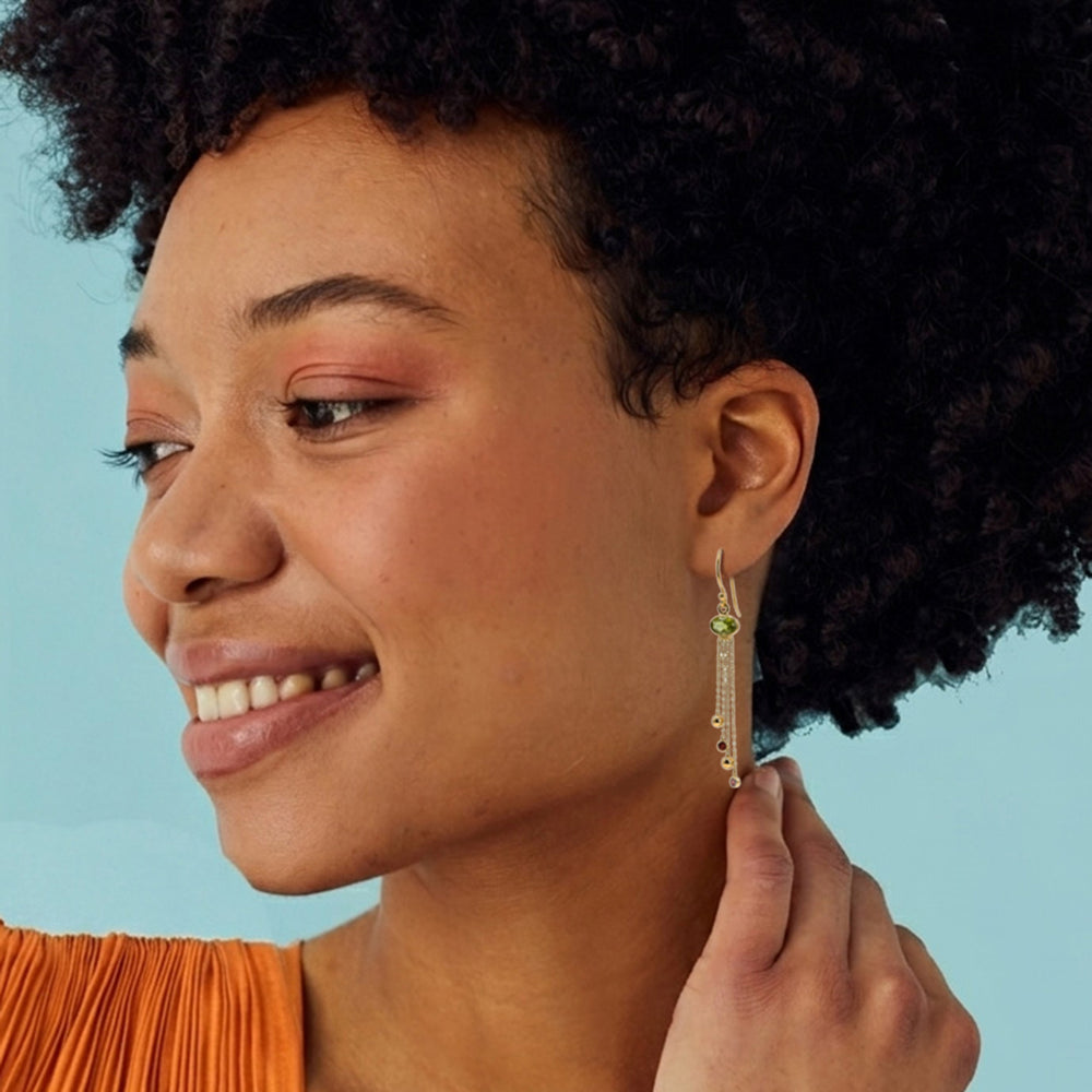 Woman wearing peridot dangle earrings with garnets in gold.