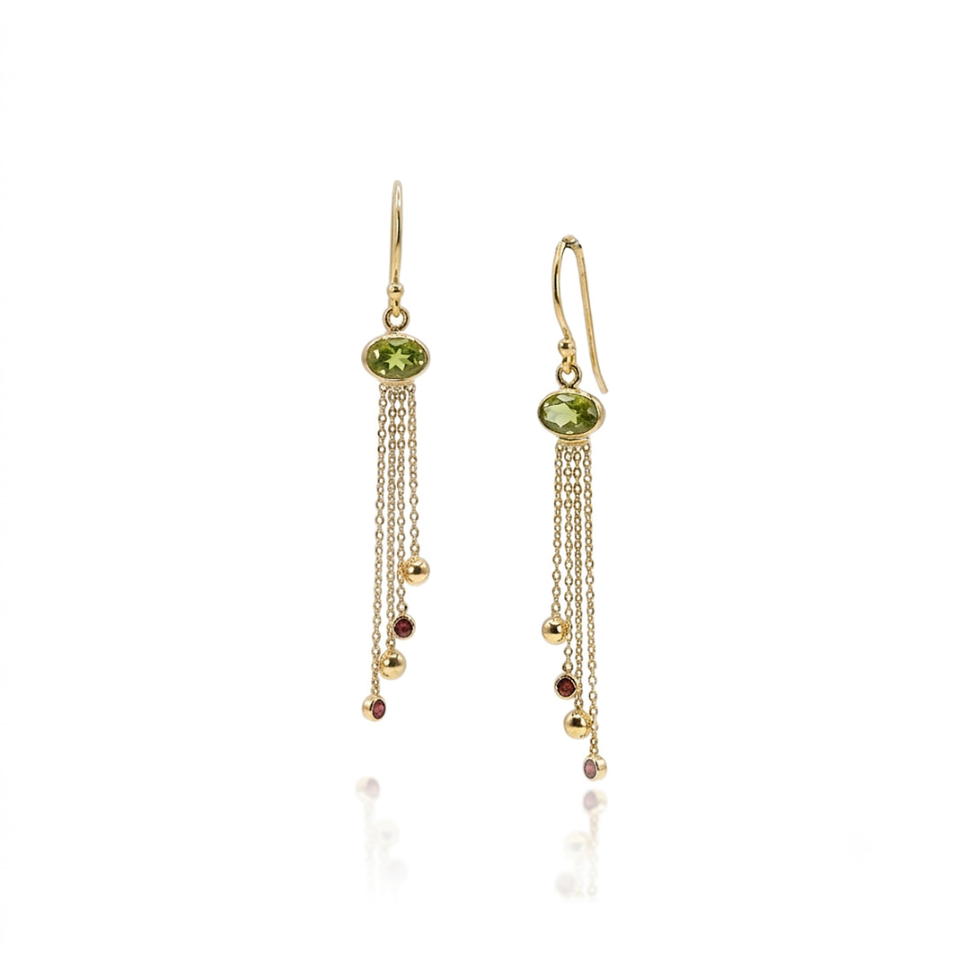Gold drop earrings with peridot gemstones and chain drops with garnets on white background.