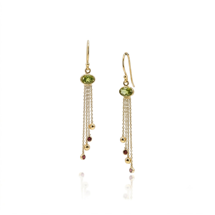 Gold drop earrings with peridot gemstones and chain drops with garnets on white background.