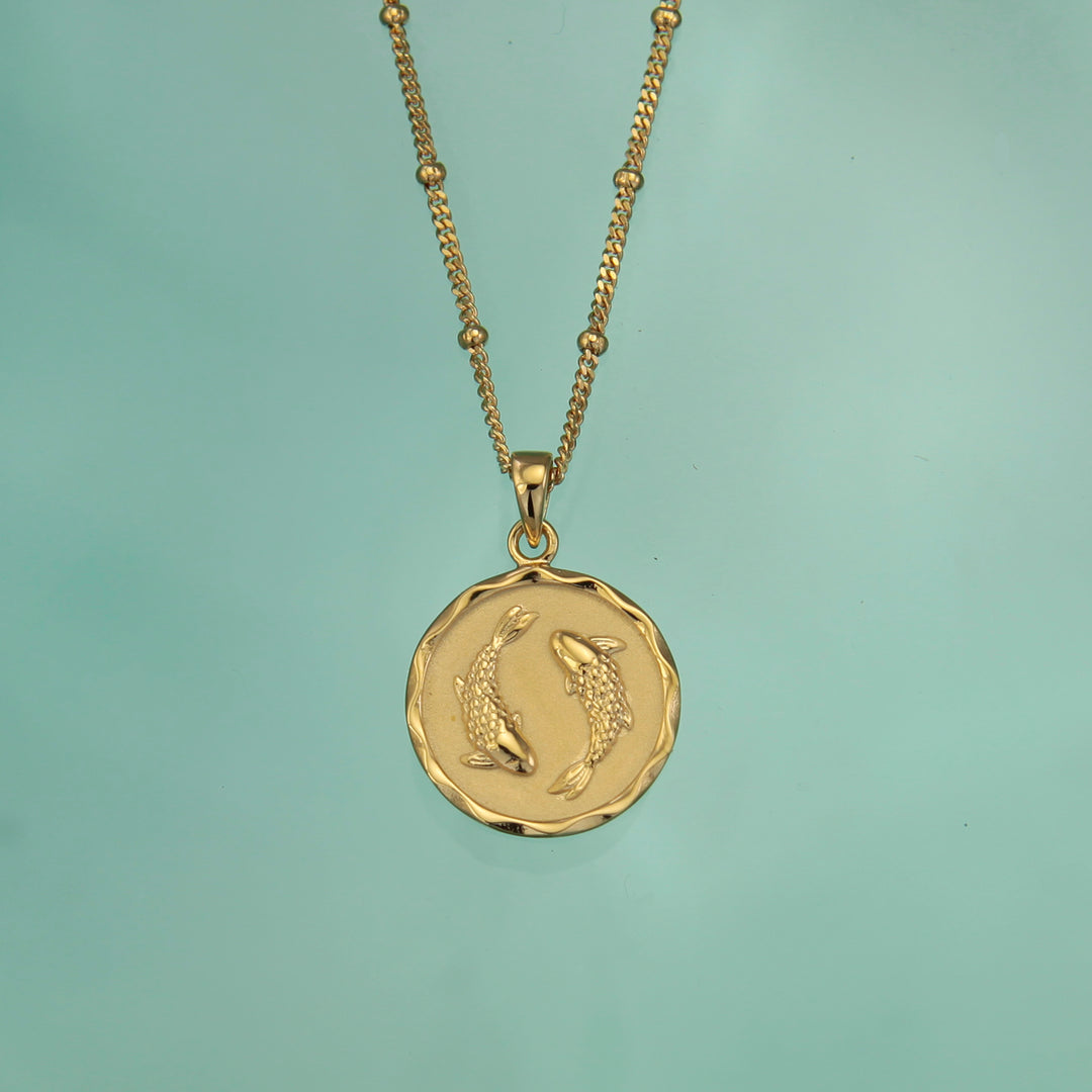 18ct gold vermeil Pisces zodiac star sign pendant necklace on a teal background