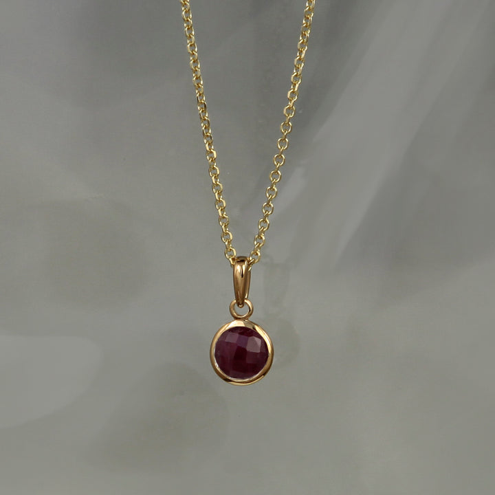 Ruby pendant set in gold vermeil with chain on a gray background