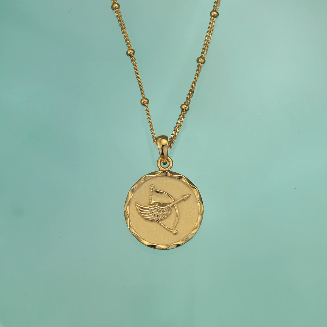 Gold Sagittarius zodiac star sign necklace pendant on an aqua background