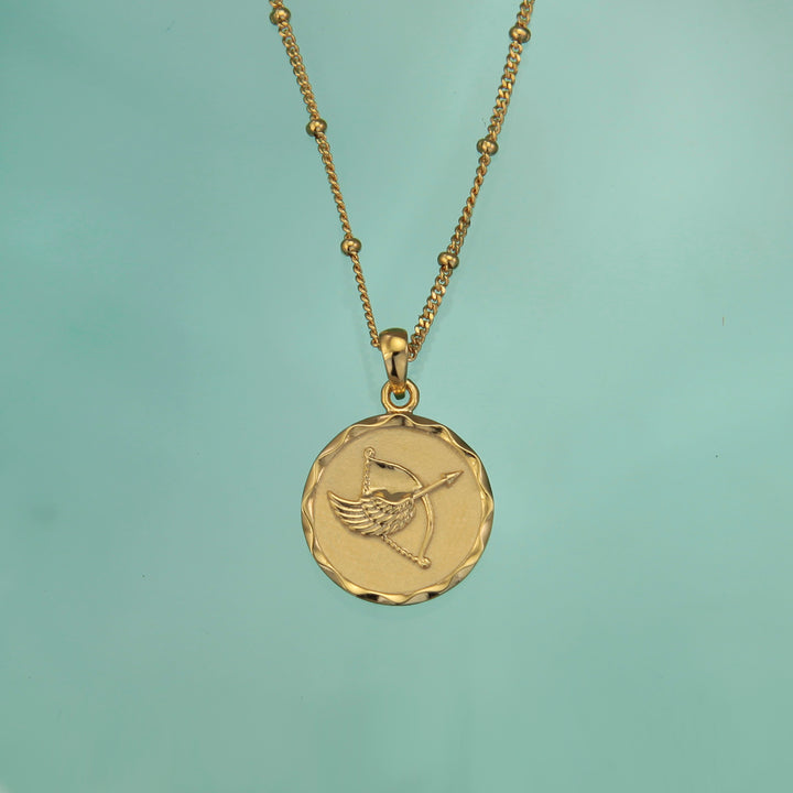 Gold Sagittarius zodiac star sign necklace pendant on an aqua background
