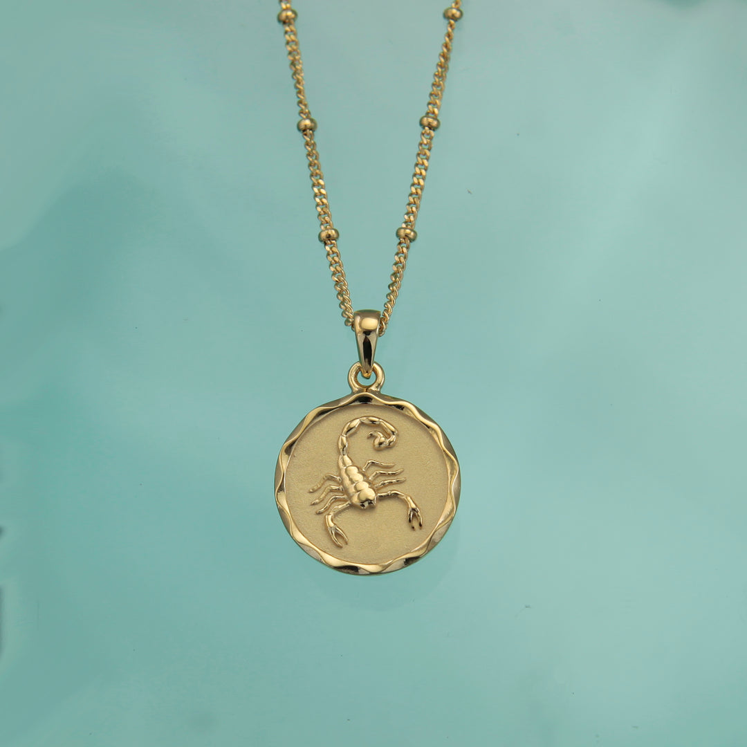18ct gold Scorpio zodiac star sign necklace pendant on a teal background