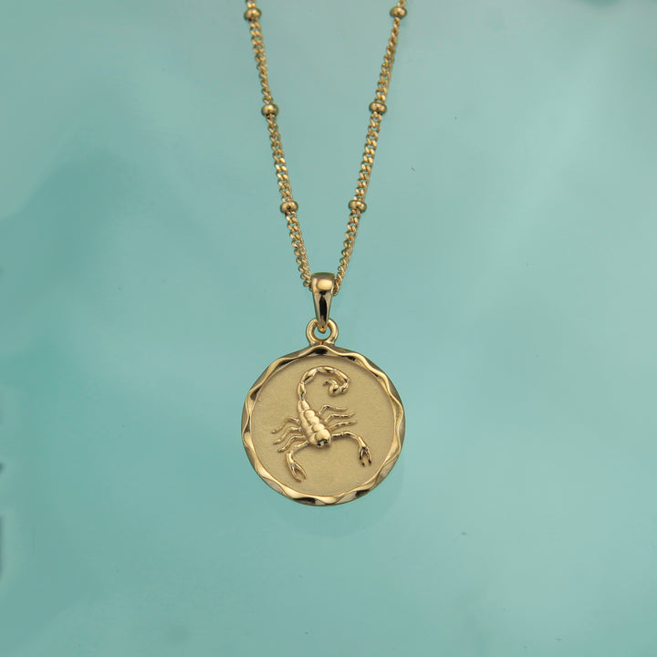 18ct gold Scorpio zodiac star sign necklace pendant on a teal background