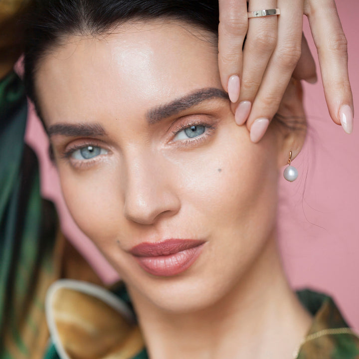 Side view of model wearing sold short drop pearl earrings.