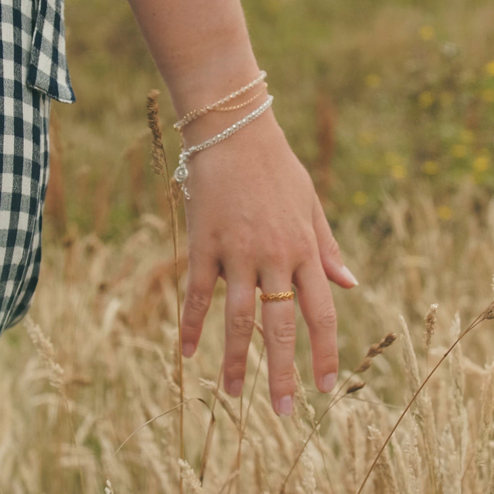Model wearing silver and gold moonstone beaded bracelets.