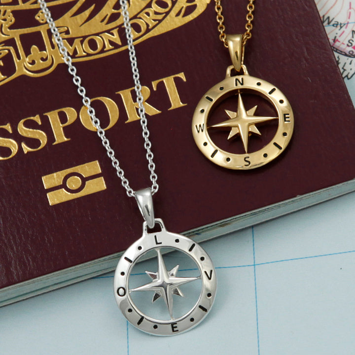 Silver and gold compass necklaces on top of a passport