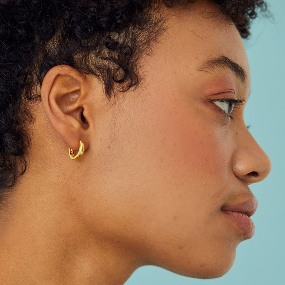 SIde view of model wearing gold hoop earrings