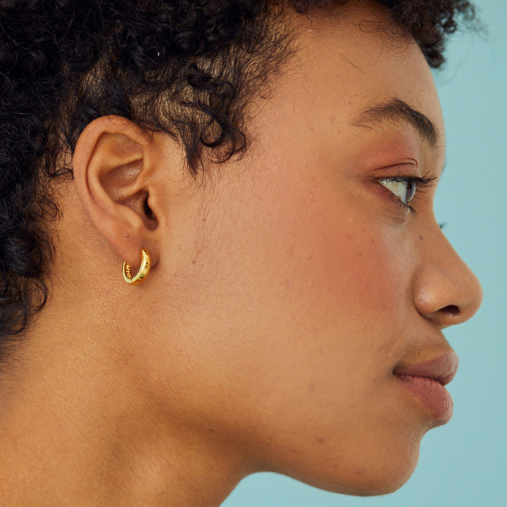 SIde view of model wearing gold hoop earrings