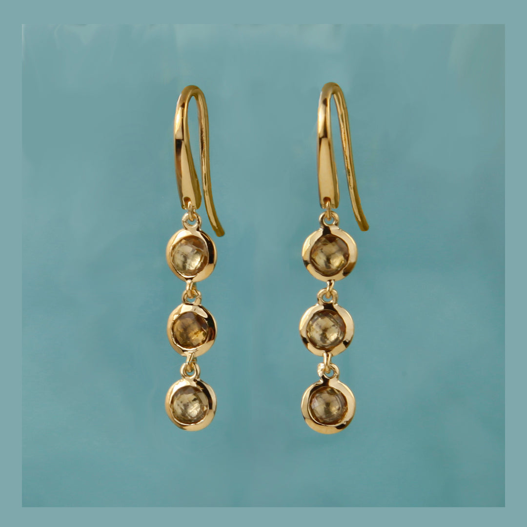 Gold and smoky quartz drop hook earrings against an aqua background