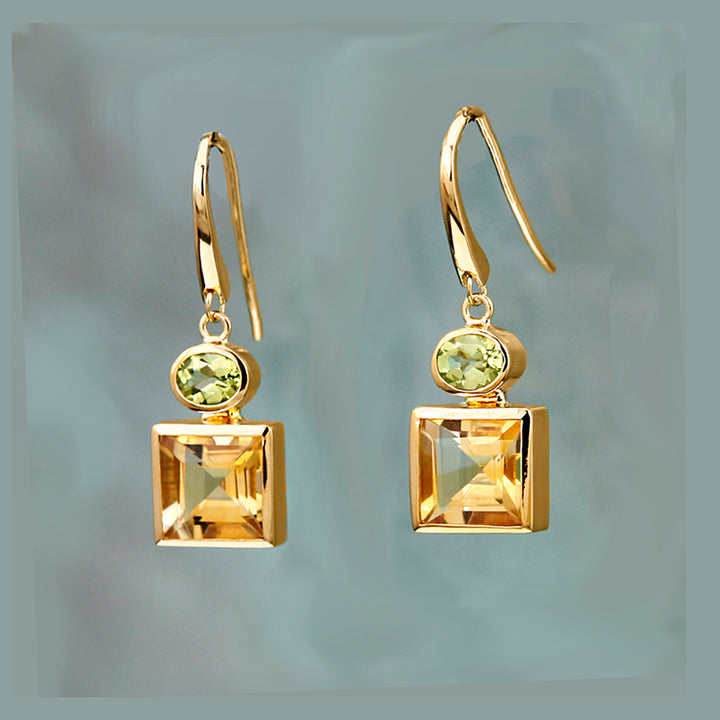 Gold earrings with citrine and peridot gemstones on a turquoise background