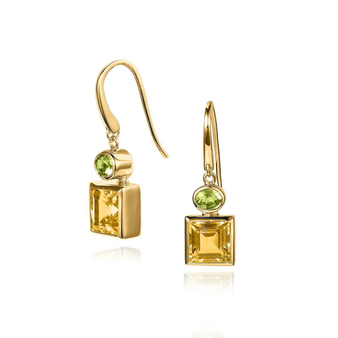Gold hook earrings with square yellow and oval green gemstones on a white background