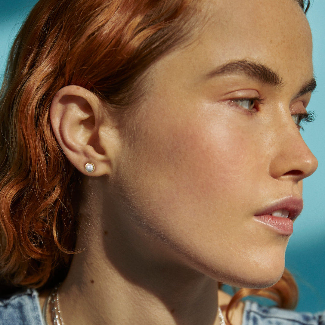 Model wearing gold pearl stud earrings