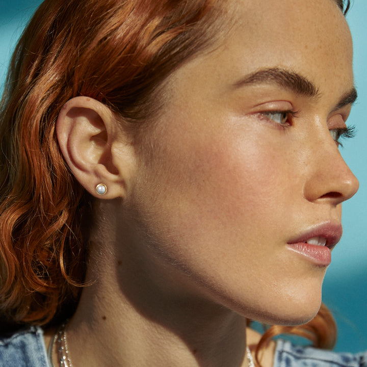 Model wearing gold pearl stud earrings