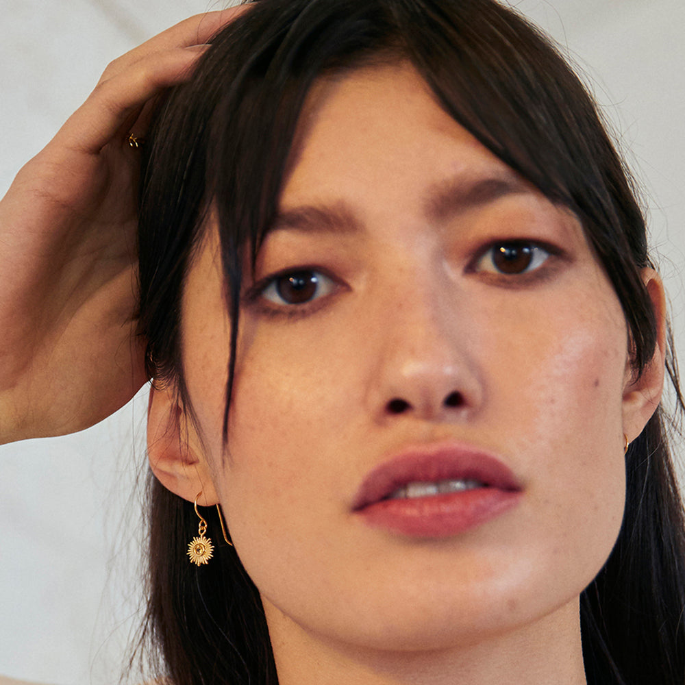 Model wearing gold sun hook earrings featuring citrine gemstones